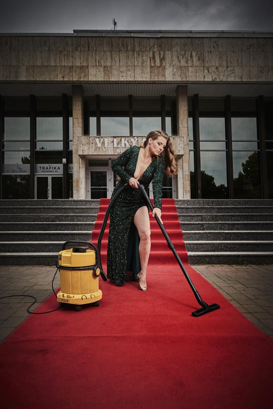 herečka s vysavačem na červeném koberci