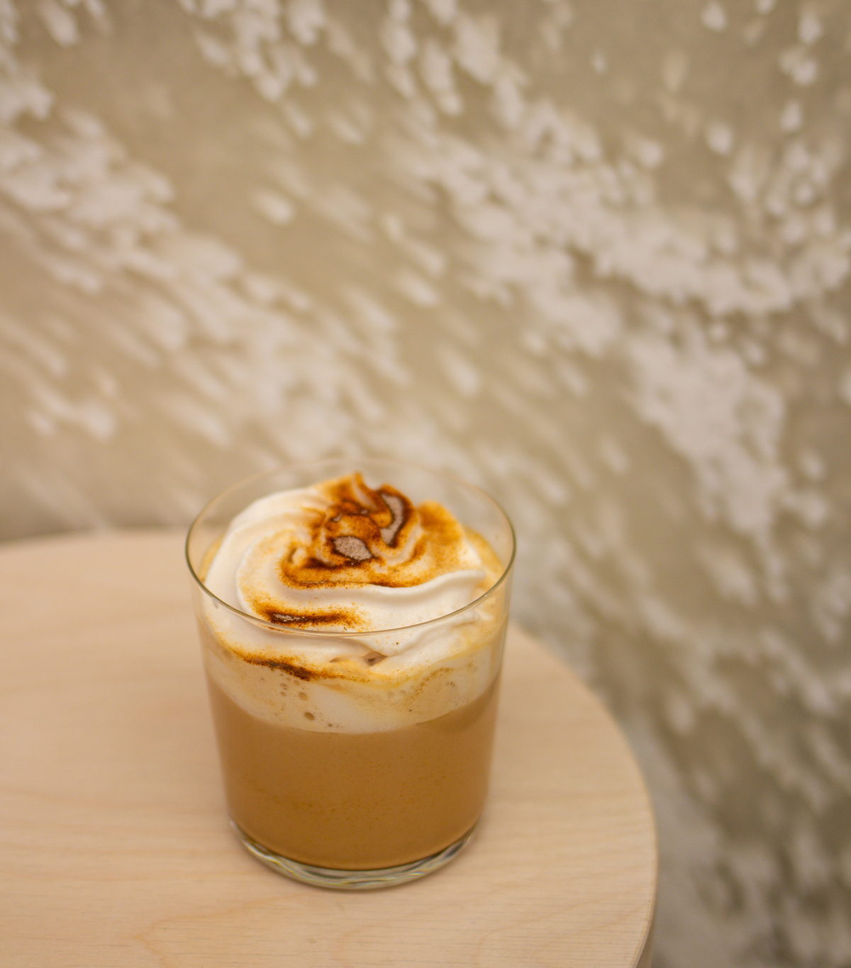 Royal chai latte s malinovou pěnou ve sklenici na stolku v kavárně.