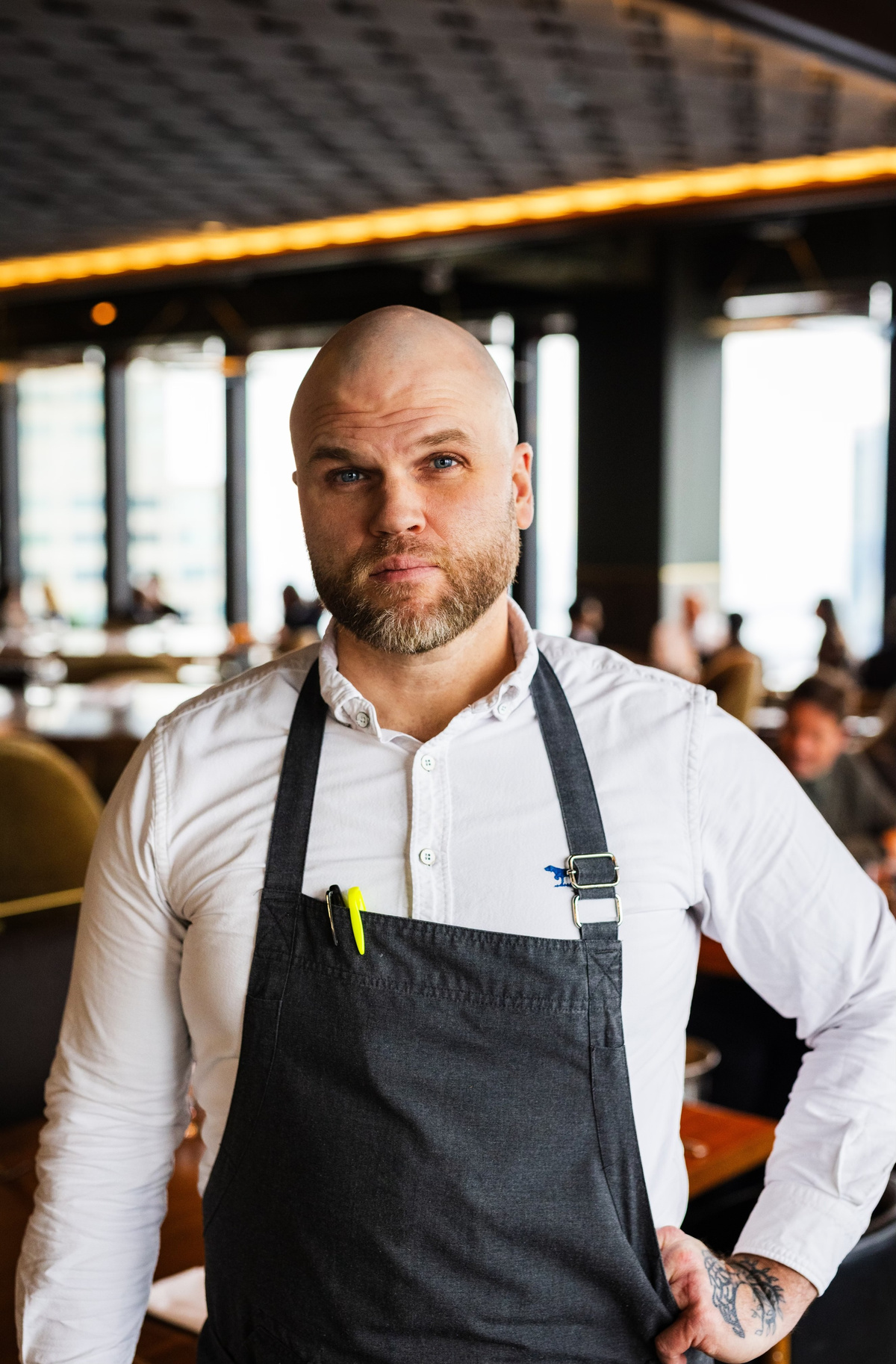 Šéfkuchař v zástěře stojí v interiéru moderní restaurace.