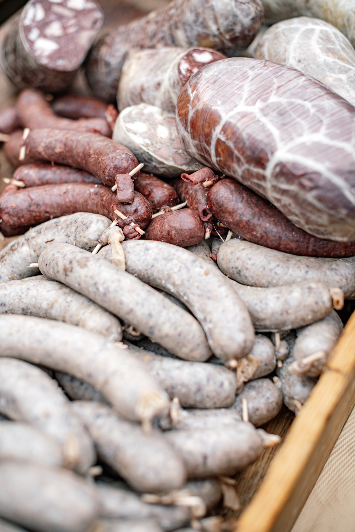 Detail zabijačkových specialit – jitrnice, jelita a tlačenka naskládané v dřevěné bedýnce.