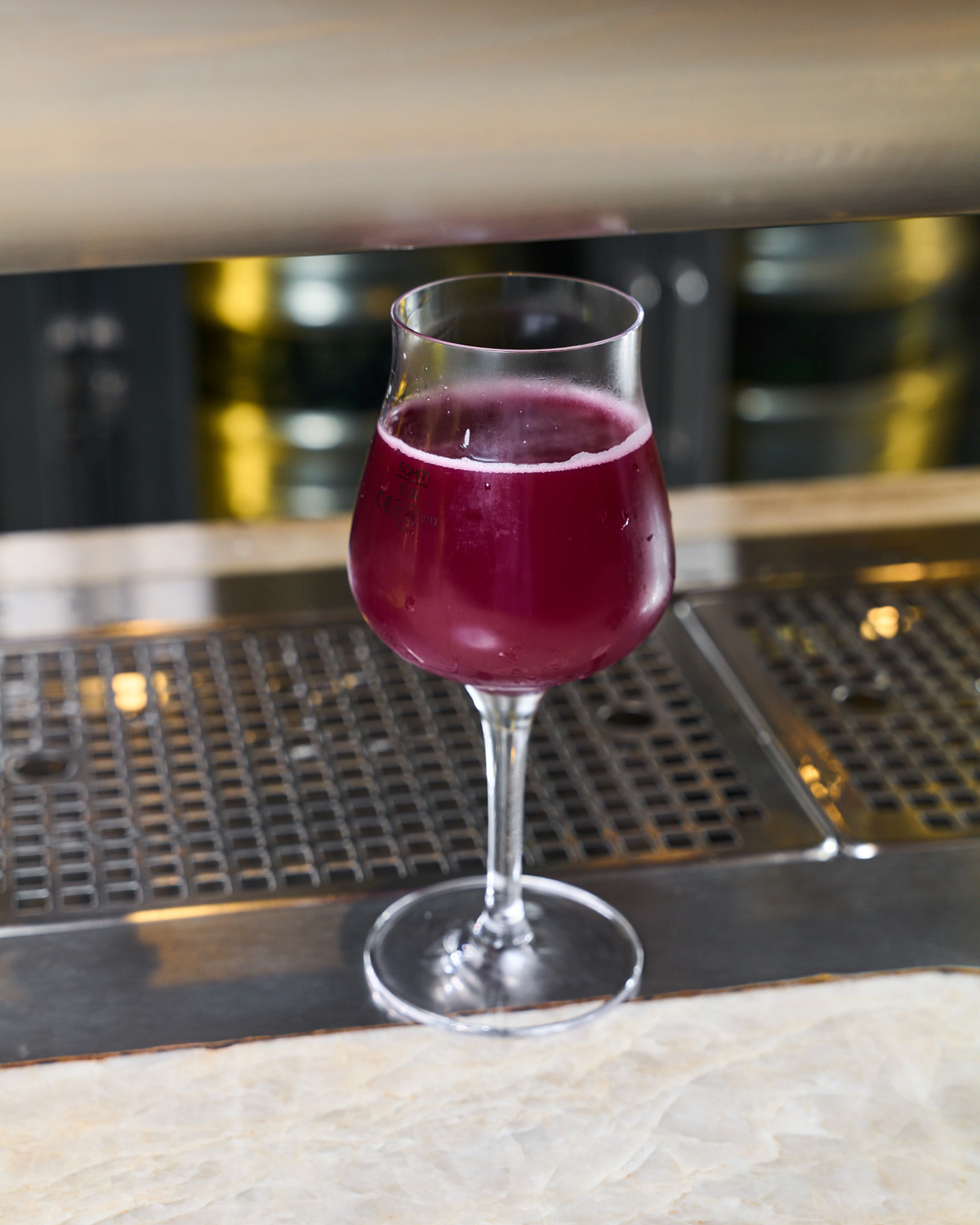 Sklenice s červenofialovým pivem na barovém pultu u výčepu.