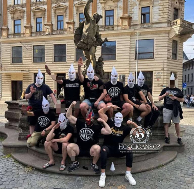 Hajlující lidé v bílých kápích