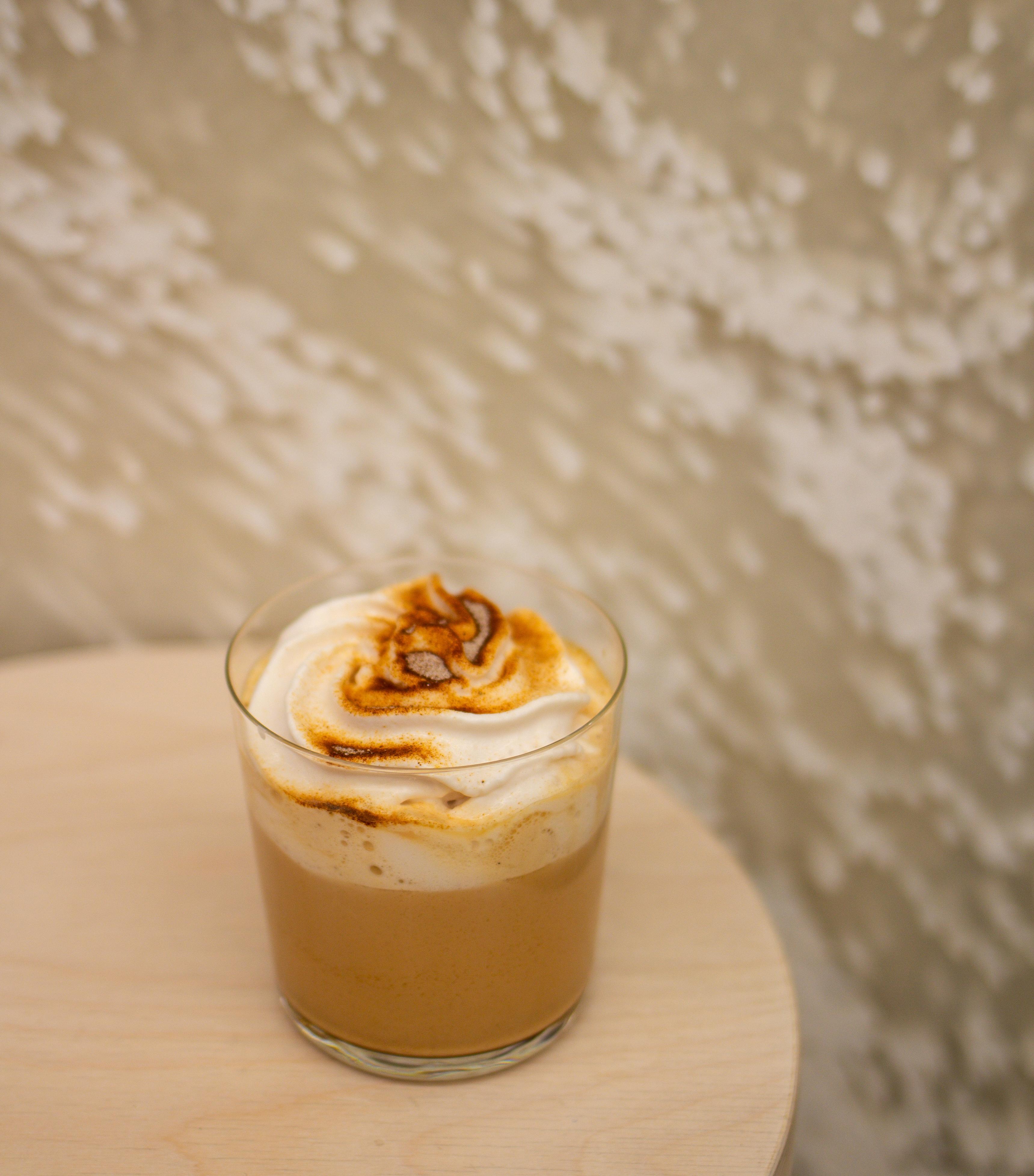 Royal chai latte s malinovou pěnou ve sklenici na stolku v kavárně.