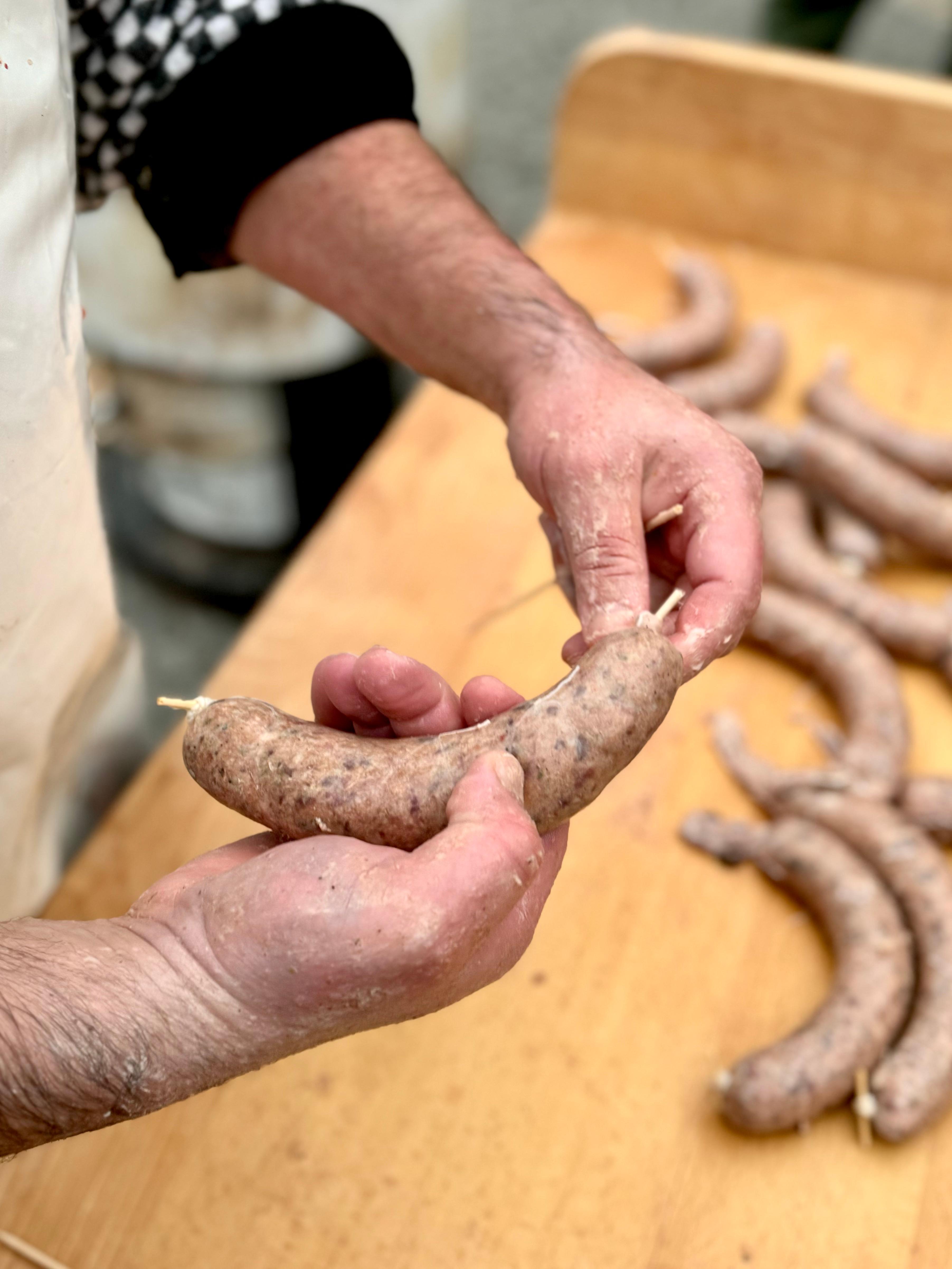 Řezník při přípravě jitrnic na dřevěném stole během tradiční české zabijačky v Lokálu.