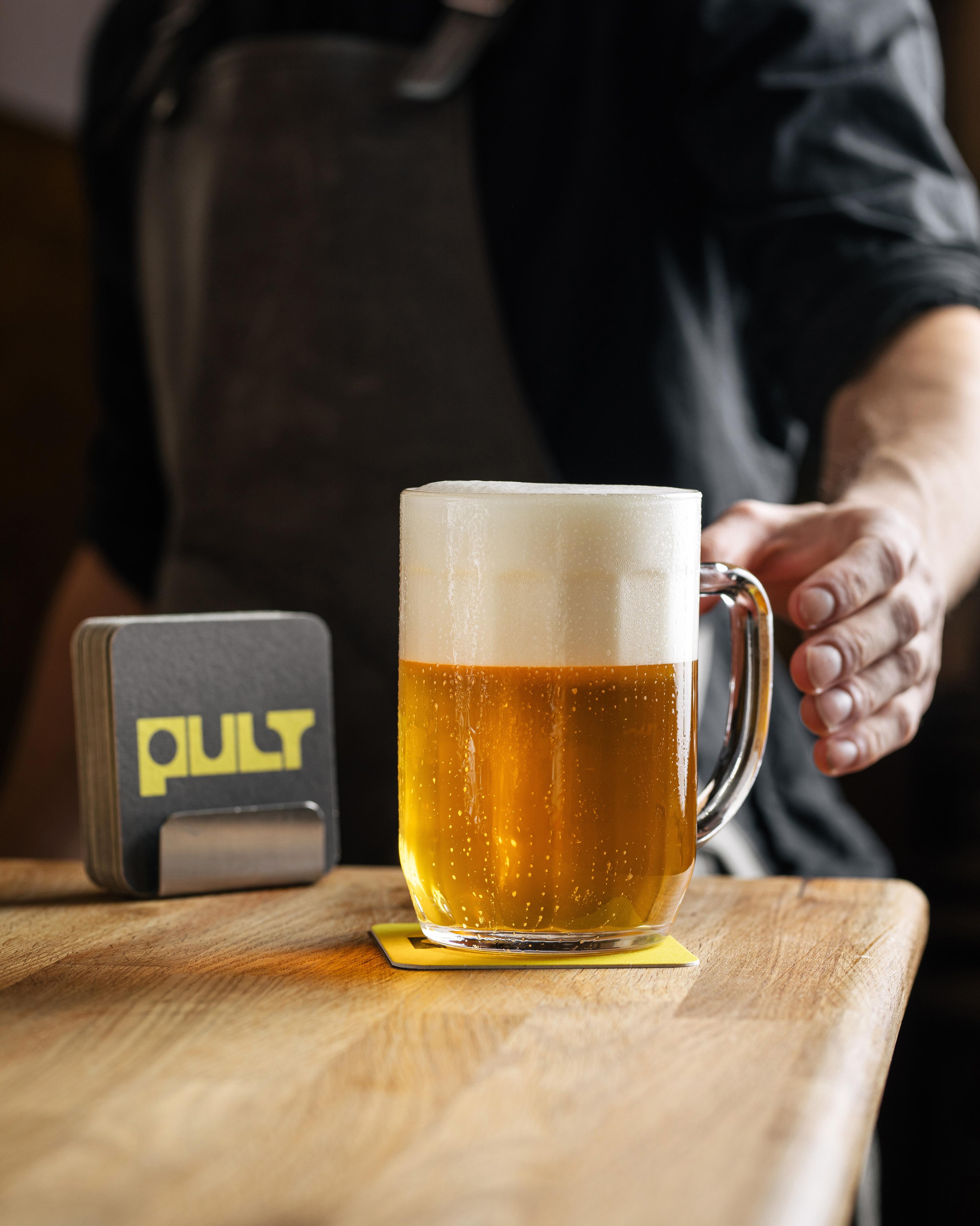 Čerstvě načepované pivo s hustou pěnou na dřevěném stole v Pultu.