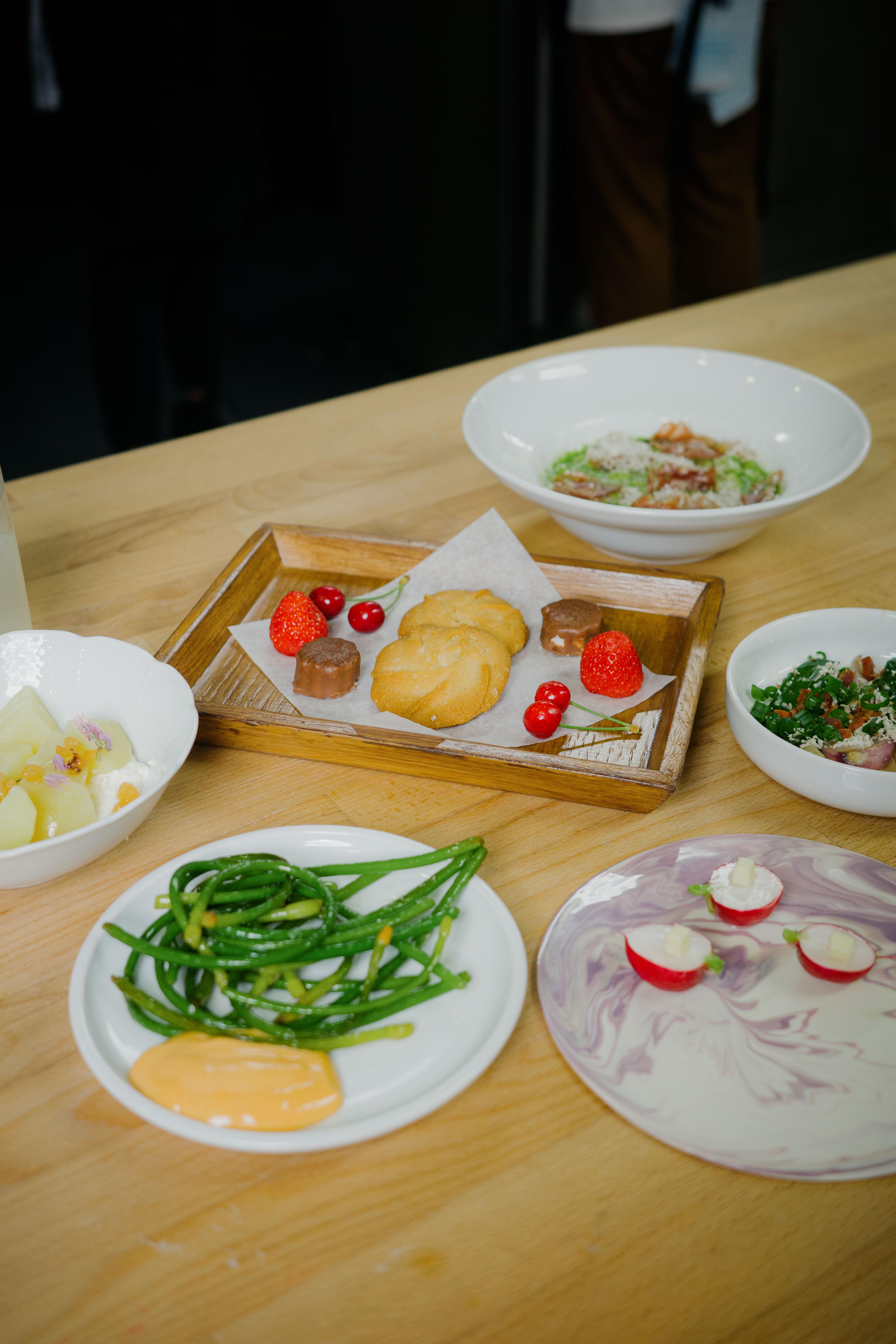 Výběr malých pokrmů a dezertů servírovaných na talířích na kuchyňském pultu.