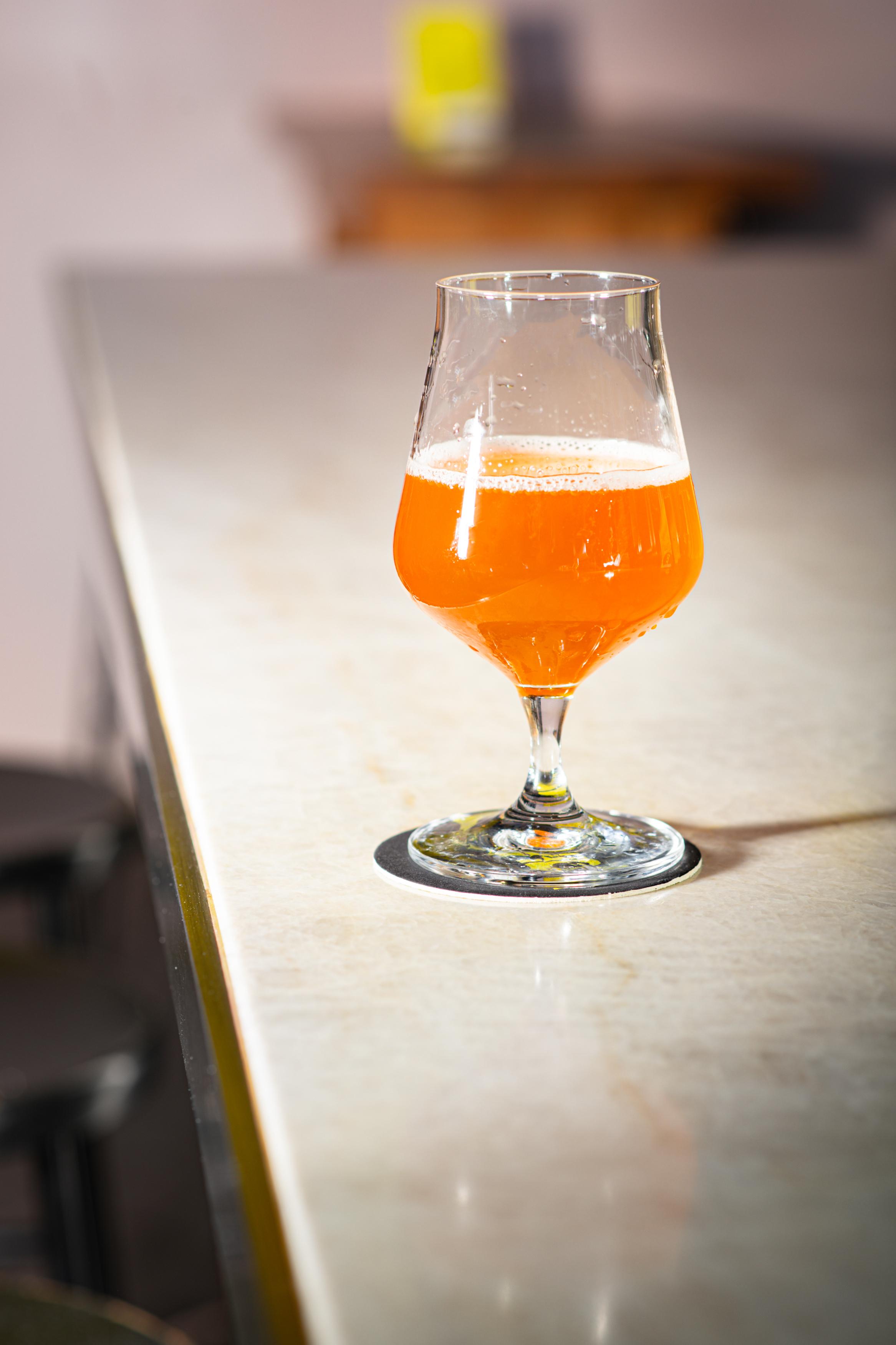Sklenice oranžového piva na tácku na barovém pultu.