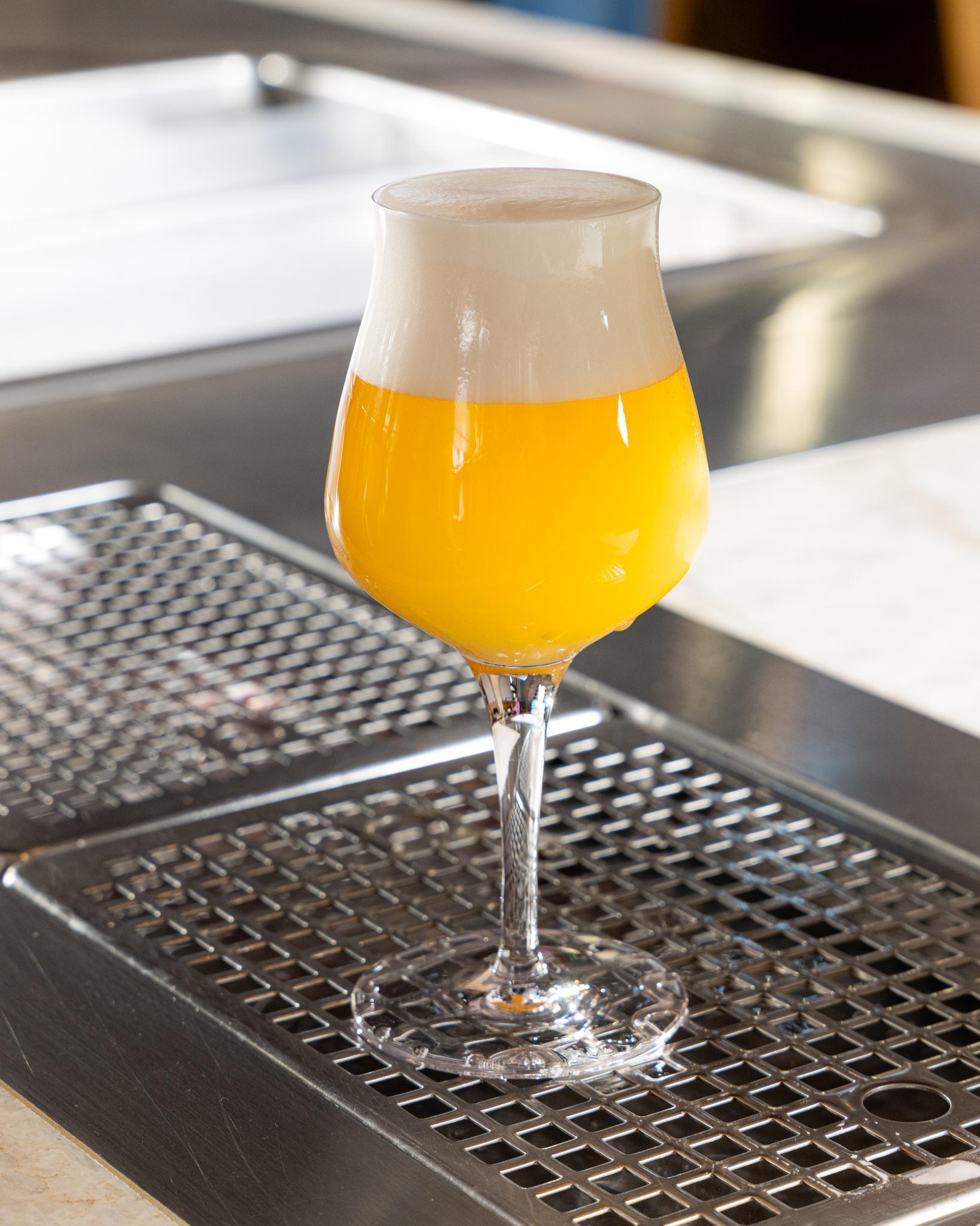 Čepované řemeslné pivo s hustou pěnou ve sklenici na výčepu.