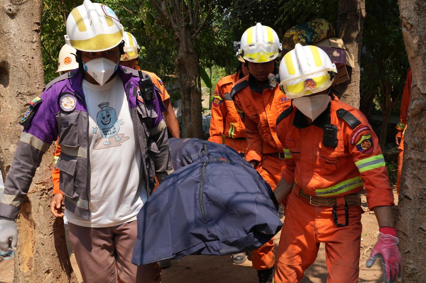 Záchranáři vynášejí mrtvé tělo z jedné ze zřícených budov při pátečním zemětřesení v Barmě