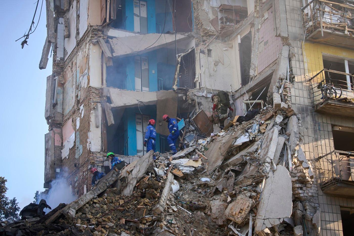 Záchranáři pátrájí v sutinách obytného domu v Kyjevě po jeho obyvatelích. Hledají už většinou jen těla obětí, ale pátrají opatrně, protože pod troskami mohou být ještě živí lidé.