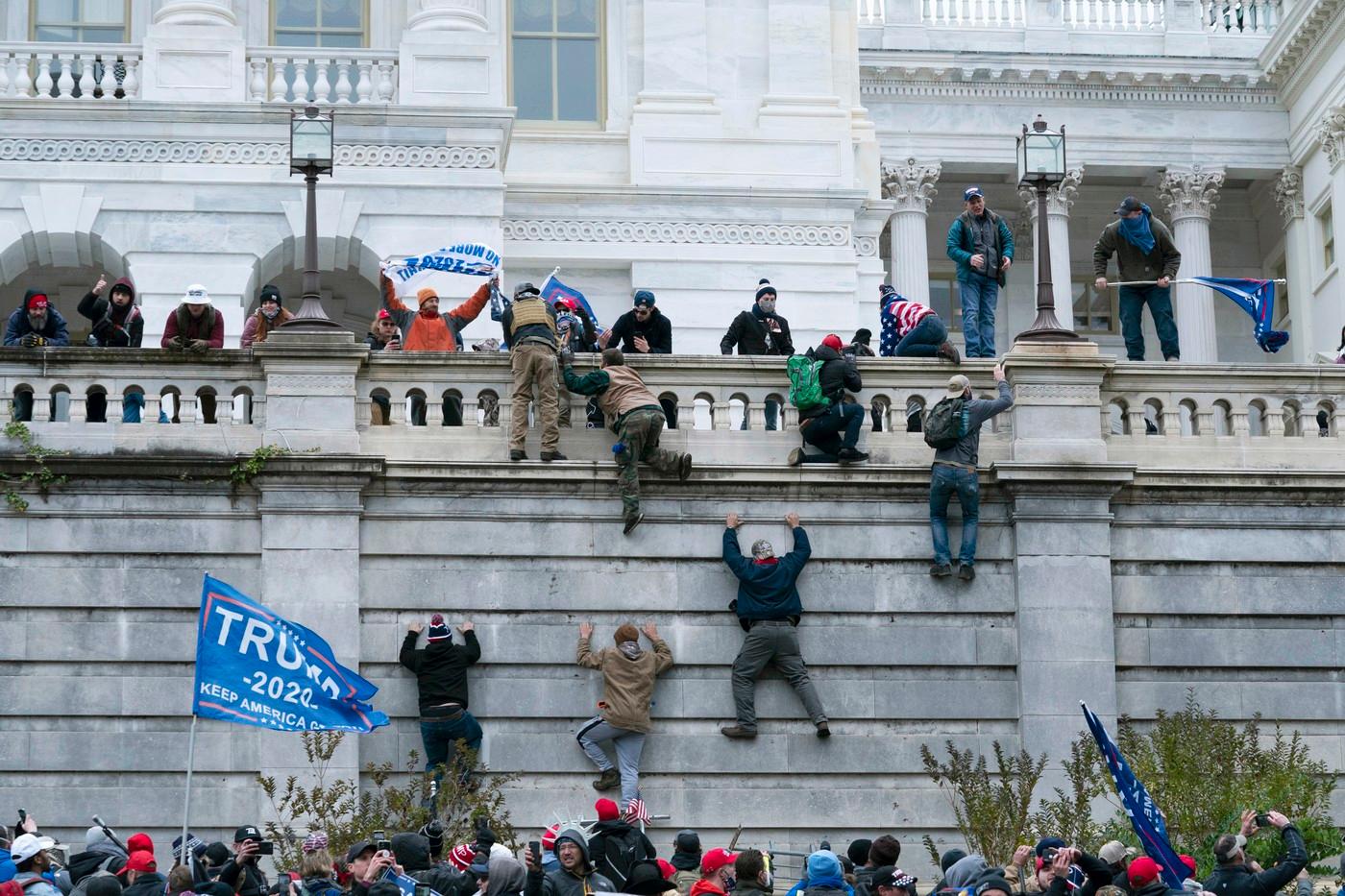 Příznivci prezidenta Donalda Trumpa šplhají ve středu 6. ledna 2021 na západní zeď Kapitolu Spojených států