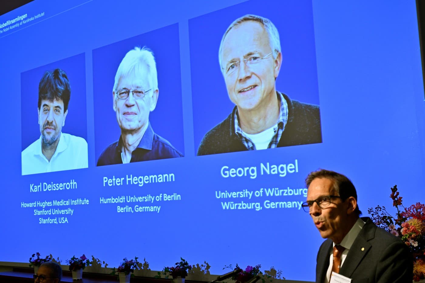 Na obrazovce jsou zachyceni Karl Deisseroth, Peter Hegemann a Georg Nagel při převzetí Nobelovy ceny za fyziologii a medicínu za rok 2026 Na obrazovce jsou zachyceni Karl Deisseroth, Peter Hegemann a Georg Nagel při převzetí Nobelovy ceny za fyziologii a medicínu za rok 2026