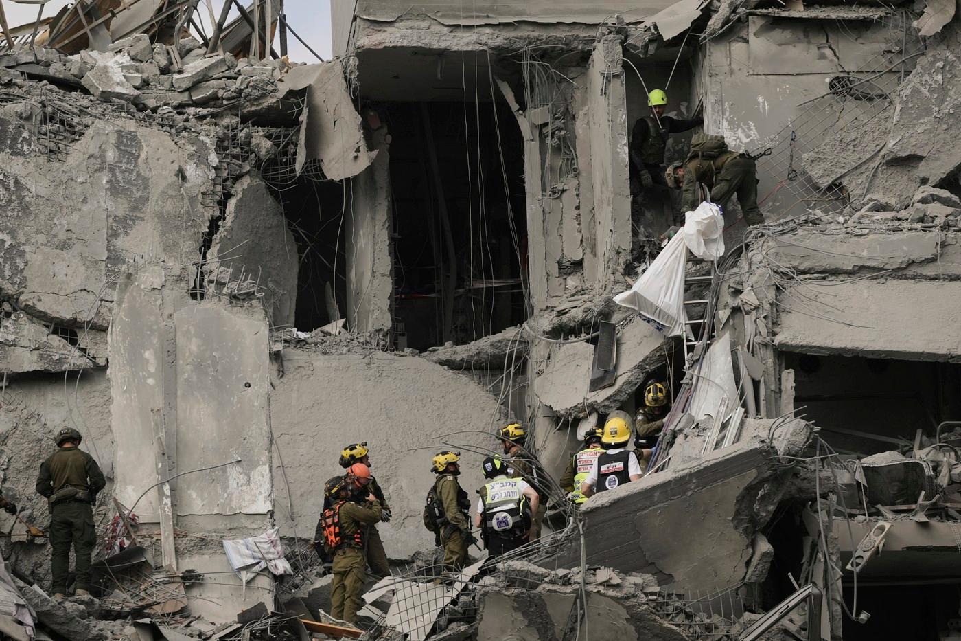 Izraelští vojáci a záchranáři pátrají v sutinách obytného domu, který zasáhla íránská raketa, po možných přeživších