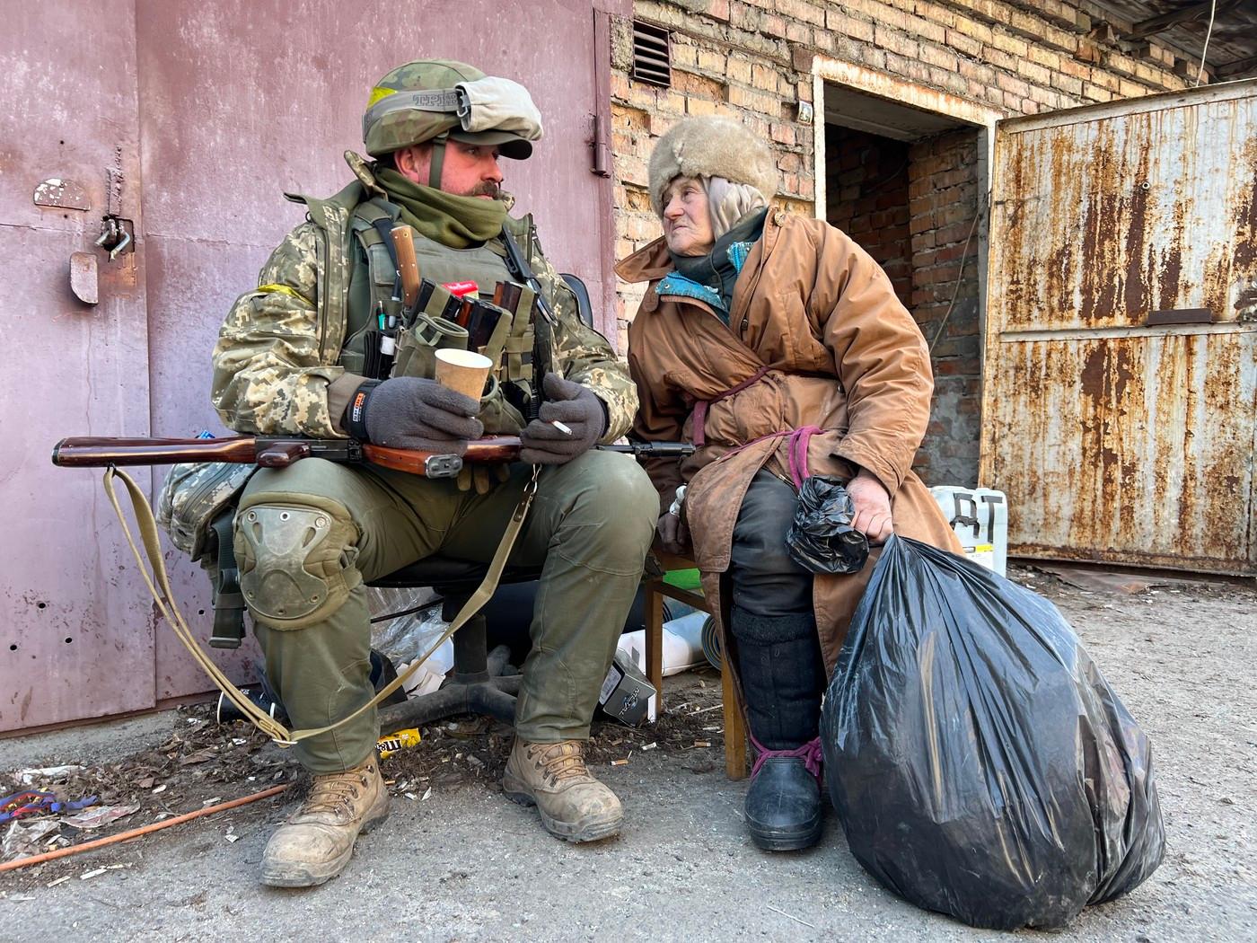 Ukrajinský obránce a místní žena poblíž první linie střetu ruských vojsk a ukrajinských obránců poblíž města Buča severozápadně od Kyjeva (11.3. 2022)