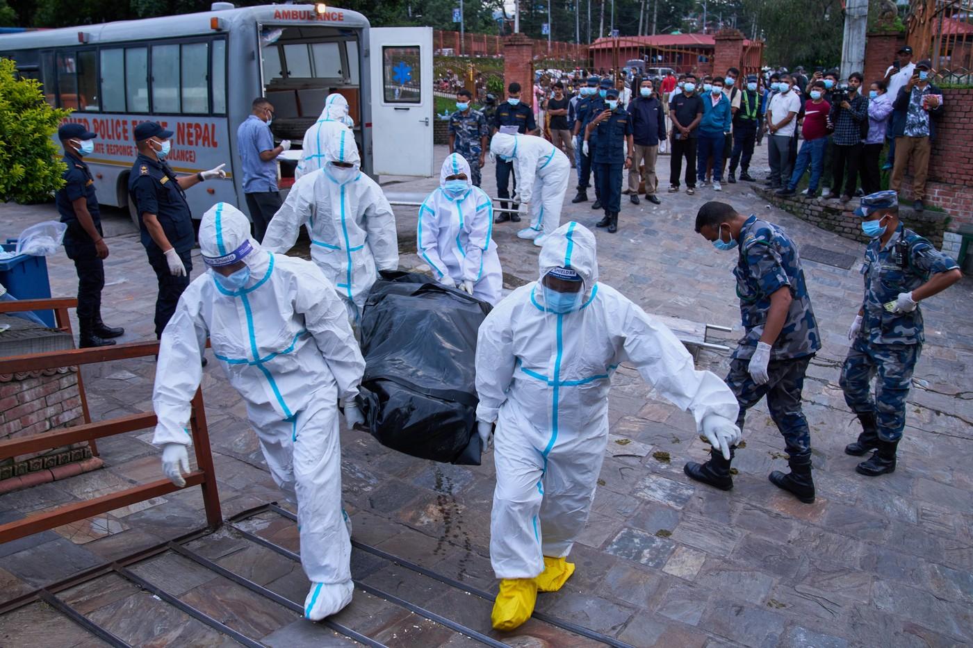 Policisté v ochranných oblecích přivážejí tělo neidentifikované oběti přívalových povodní k uložení v krematoriu v Káthmándú