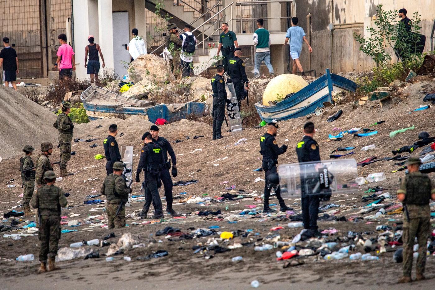 Vojáci španělské armády a příslušníci Guardia Civil stojí na stráži, zatímco se migranti vrací do Maroka ze španělské enklávy Ceuta