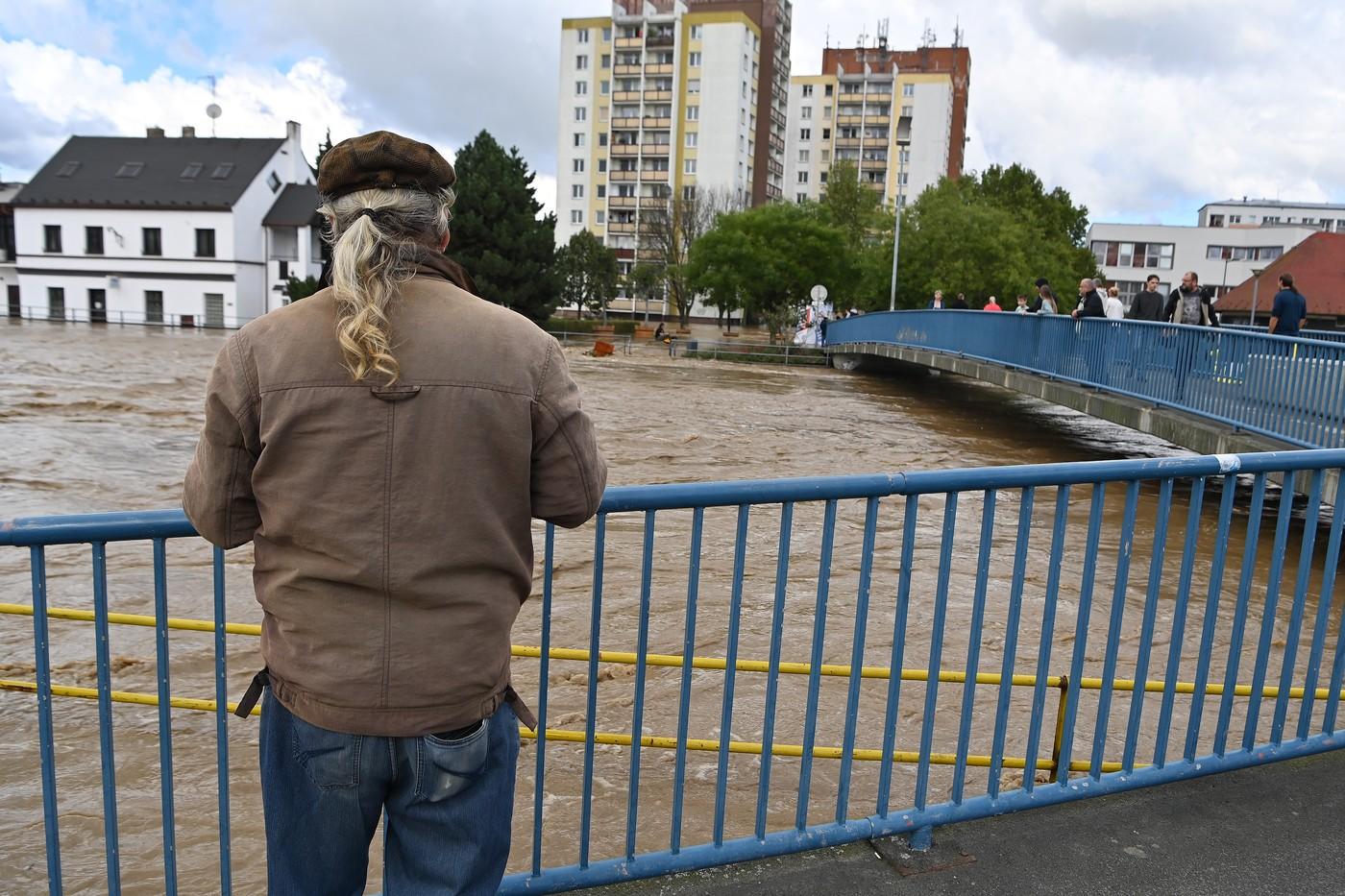 Muž sleduje rozvodněnou řeku Opavu, 15. září 2024, Opava. V pozadí je sídliště Kateřinky.