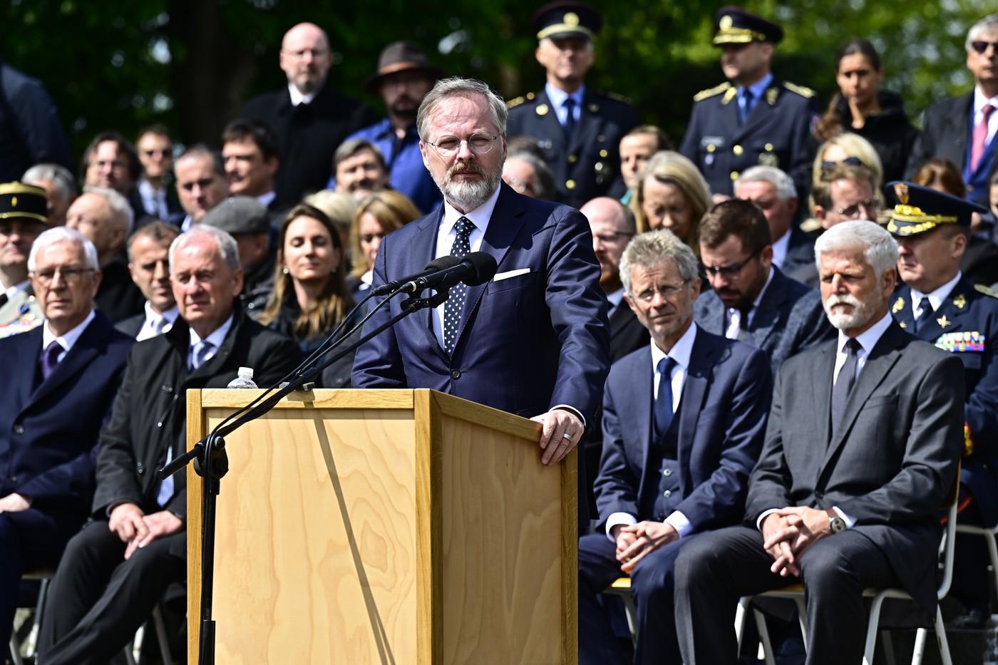 Premiér Petr Fiala hovoří na tryzně za oběti nacistické perzekuce konané u příležitosti 80. výročí osvobození, 18. května 2025, Národní hřbitov, Terezín, Litoměřicko. Za ním zprava prezident Petr Pavel a předseda Senátu Miloš Vystrčil.