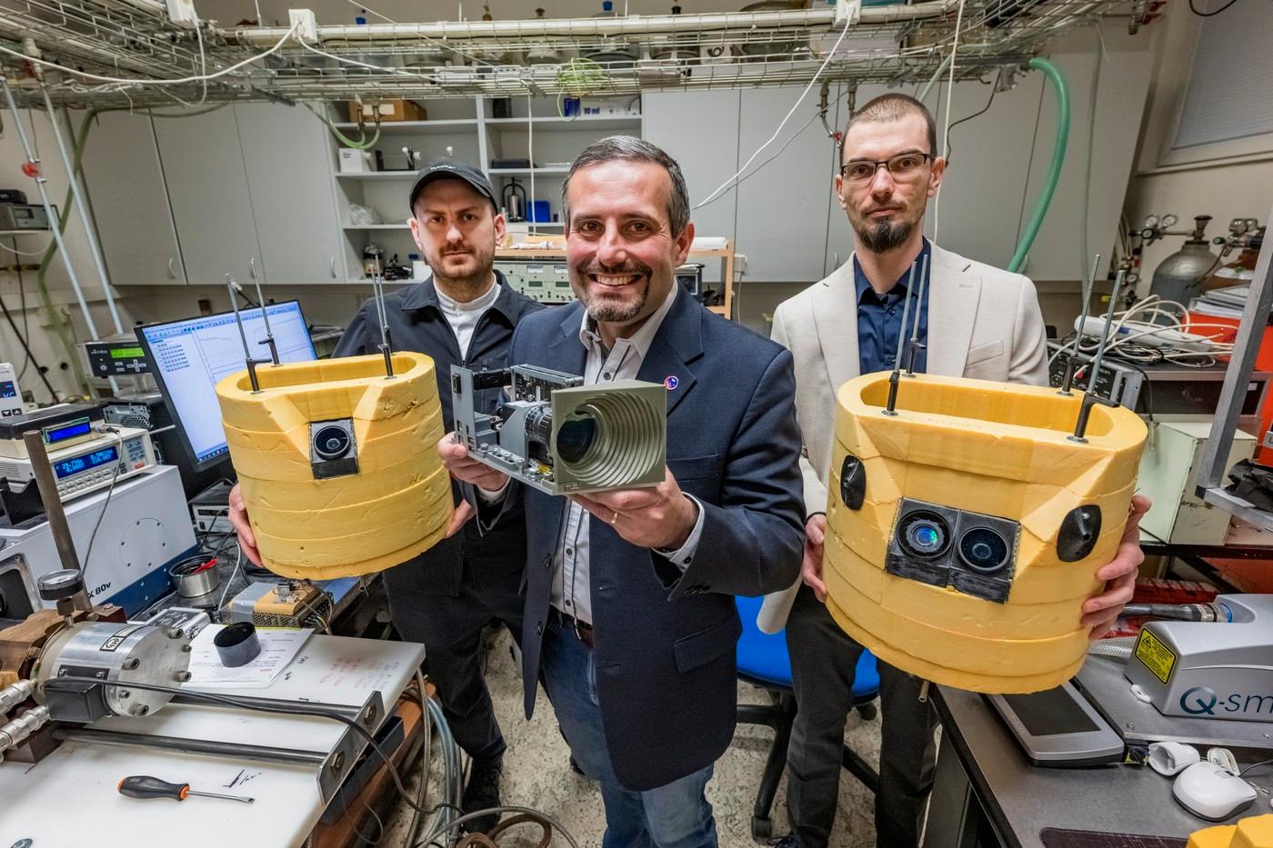 Tisková konference k projektu hyperspektrální kamery, která představuje významný krok ve vývoji českých technologií pro sledování meteorů a dalších světelných jevů v atmosféře Země z paluby satelitů, 23. dubna 2026, Ústav fyzikální chemie J. Heyrovského AV ČR, Praha. Na snímku pózuje vedoucí Oddělení spektroskopie Martin Ferus (uprostřed) s prototypem hyperspektrální kamery a technik David Černý (vlevo) a zástupce vedoucího Oddělení spektroskopie Petr Kubelík s gondolami s hyperspetrálními kamerami stratosférické mise Morana.